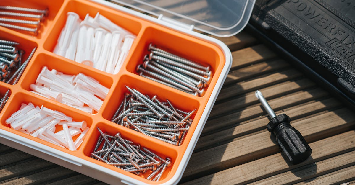 from above of container with assorted instruments placed on wooden surface near screwdriver and blac