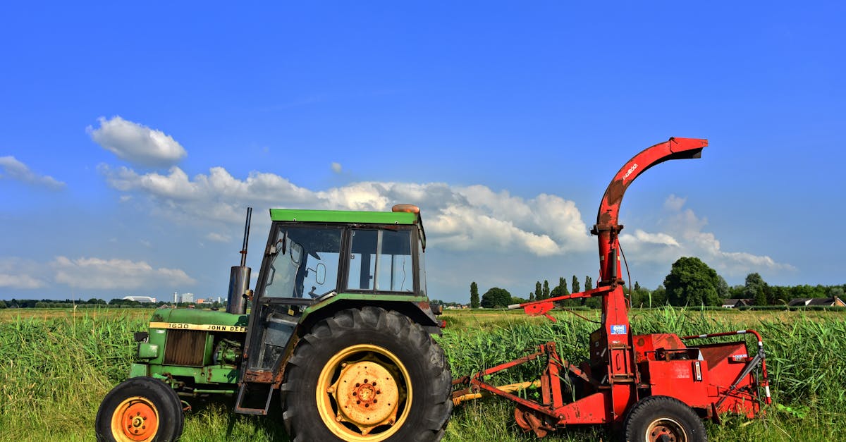 green tractor and red harvester in a vibrant rural landscape under clear blue skies