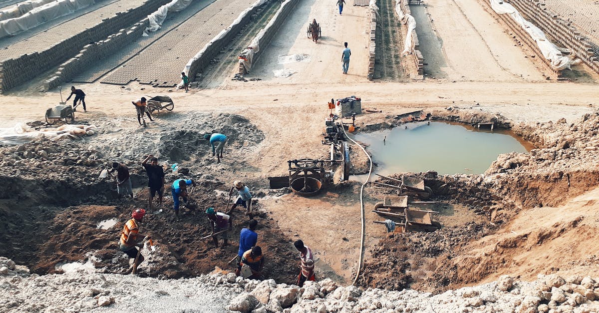 high angle view of workers digging in a construction site with soil and water in the foreground