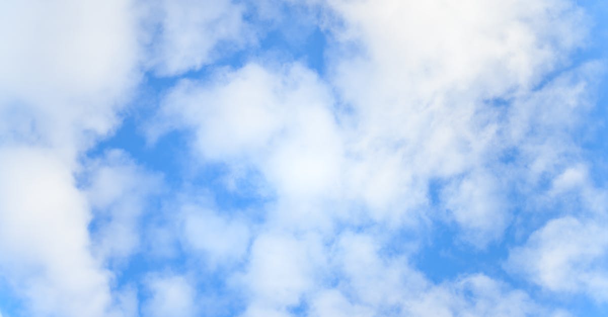 low angle of bright blue sky with floating white fluffy cumulus clouds as abstract background