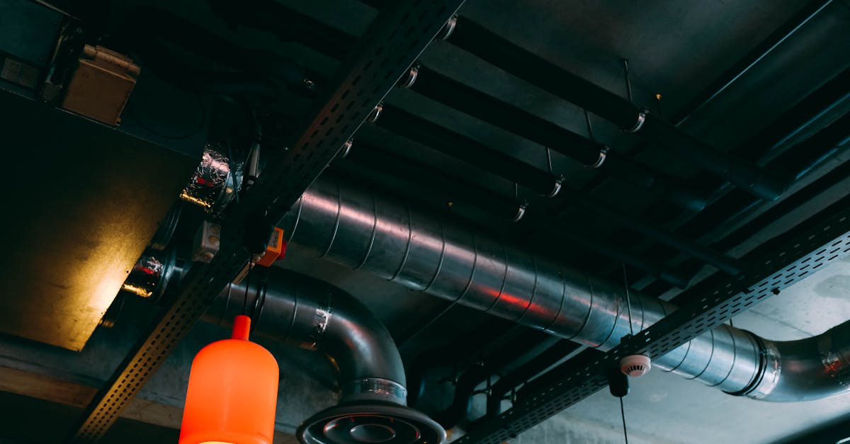 low angle view of a modern industrial ceiling featuring ducts and red lamps