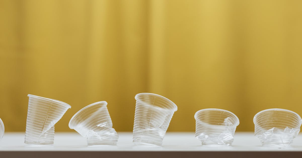 minimalist image showing crumpled plastic cups against a yellow background on a table