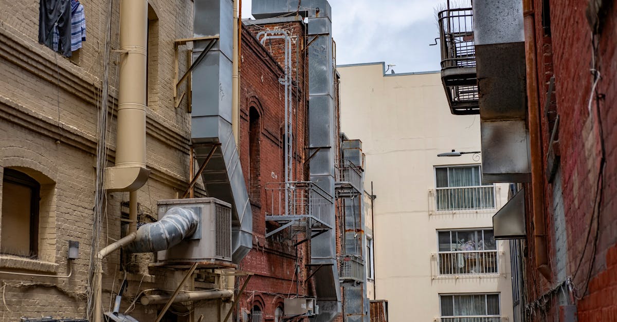 narrow urban alley with exposed industrial ventilation systems and brick walls