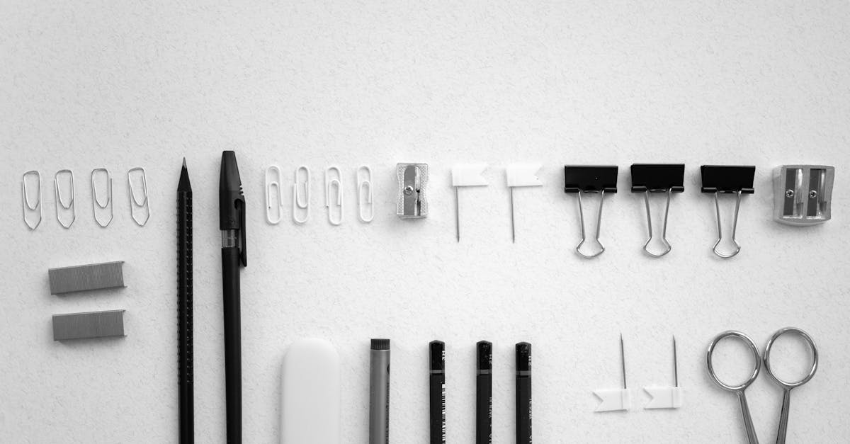 neatly arranged office supplies including scissors pens and clips on a plain white background