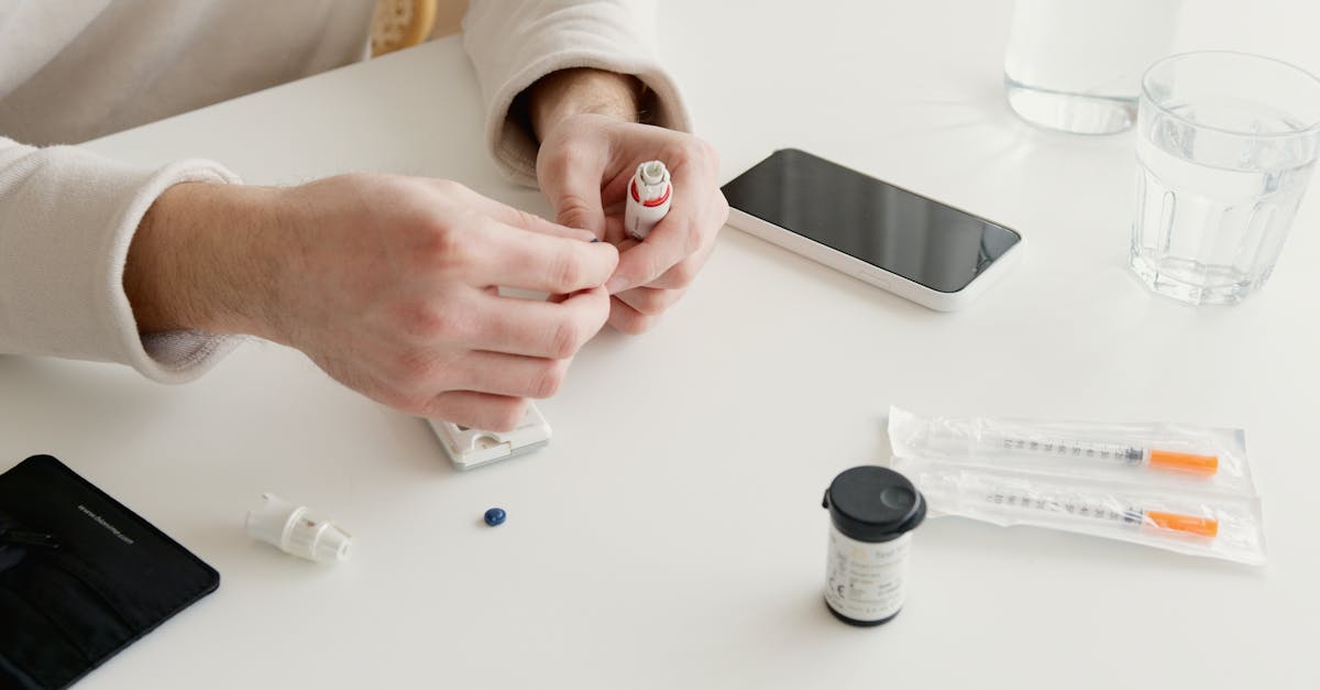 person preparing insulin injection with medical devices and glucometer on a table