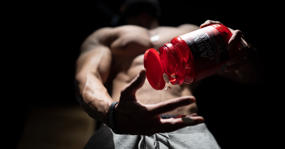 shirtless muscular man pouring protein supplements from a bottle showcasing fitness and strength