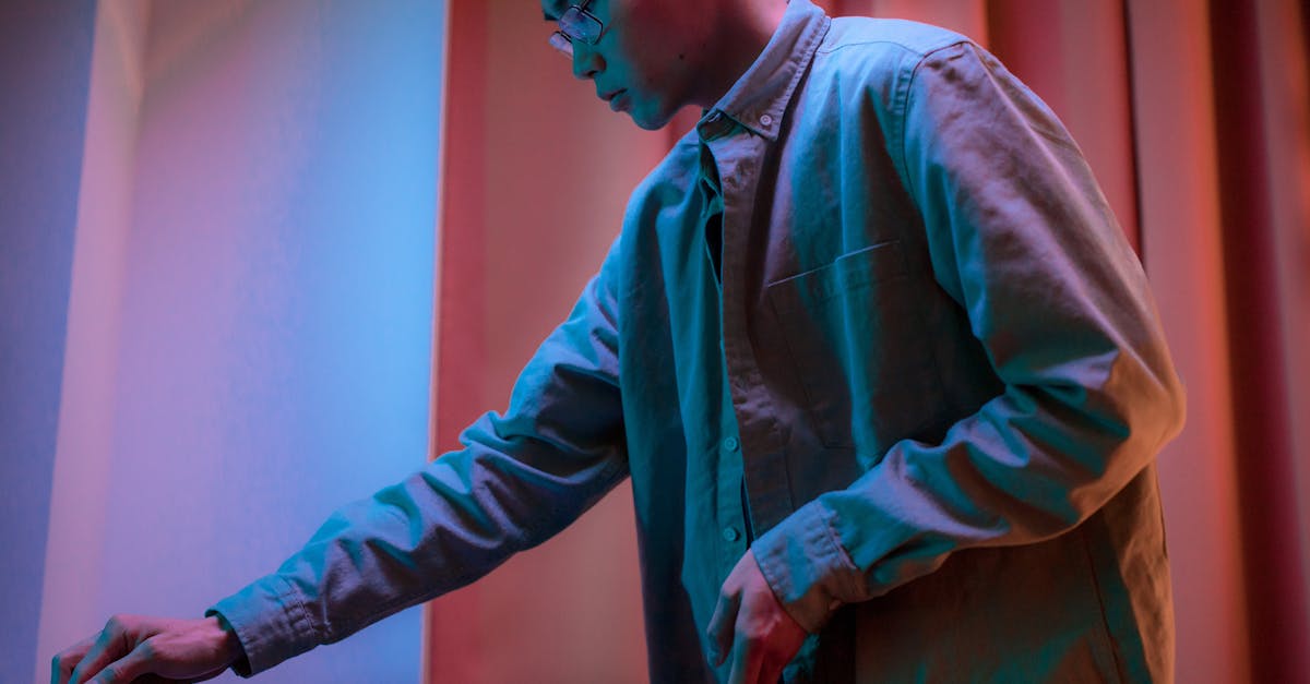 side view of an asian man adjusting equipment indoors under colorful lighting