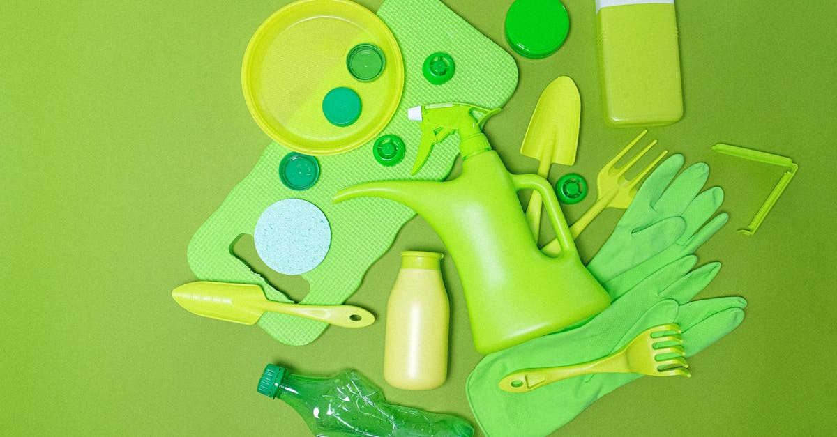 top view monochrome of various plastic bottles and kitchen utensil polluting planet on green backgro