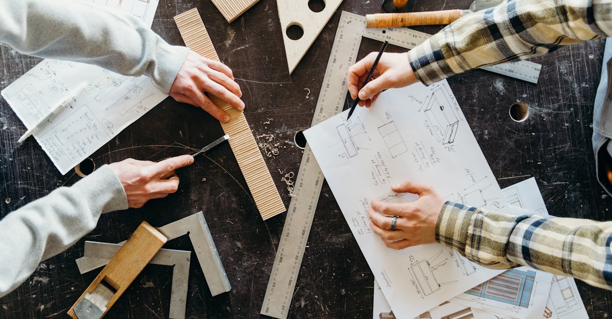 top view of two people designing and crafting woodworking projects with blueprints and tools