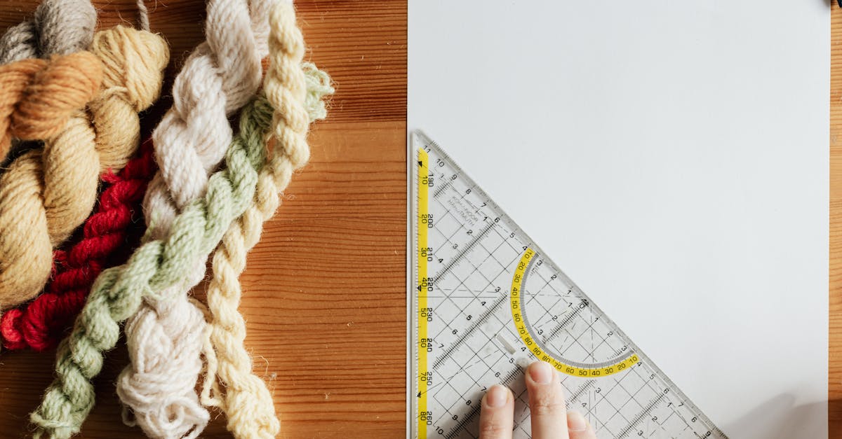 top view of unrecognizable female weaver preparing template for future carpet on piece of paper usin