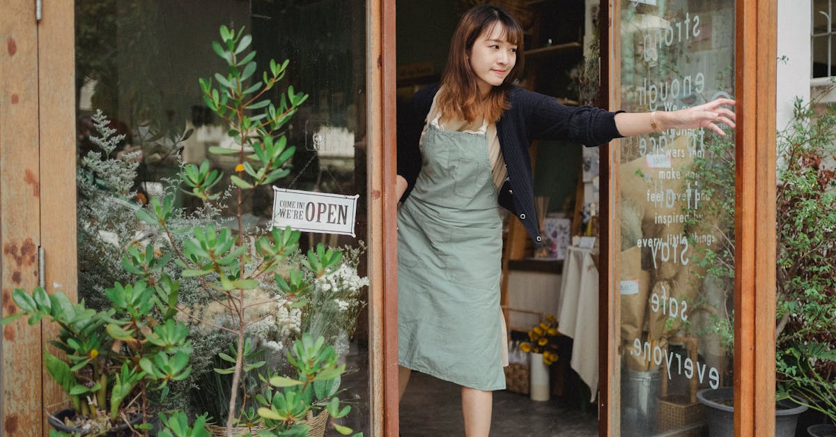 tranquil florist in apron opening glass door of flower shop in daytime in city