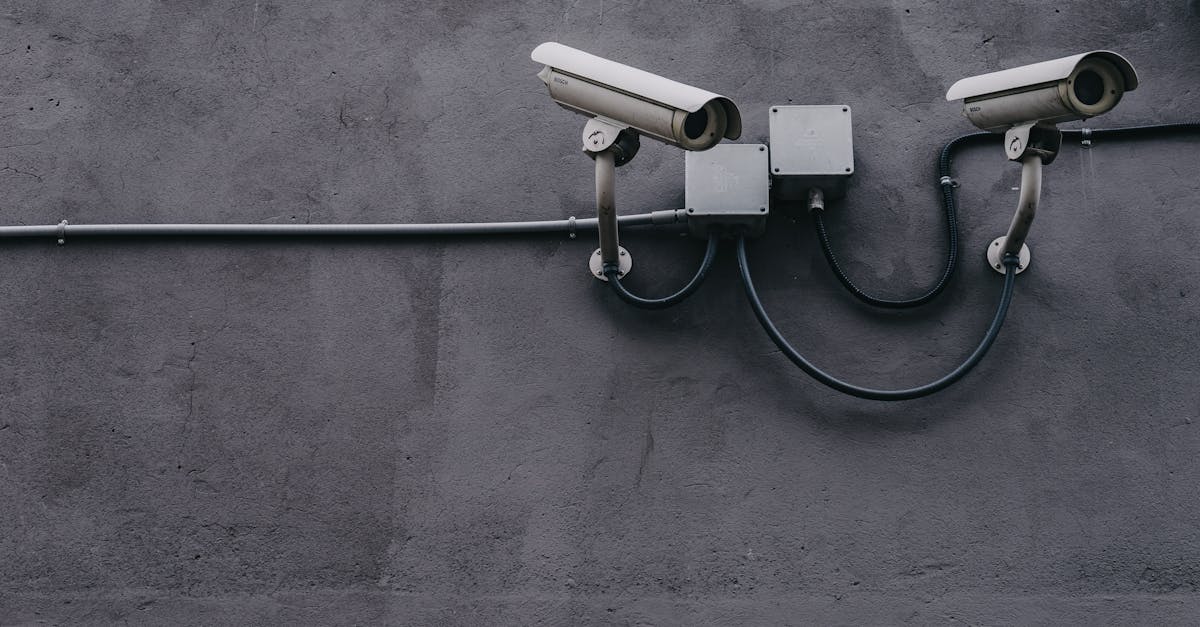 two surveillance cameras mounted on a concrete wall highlighting security technology