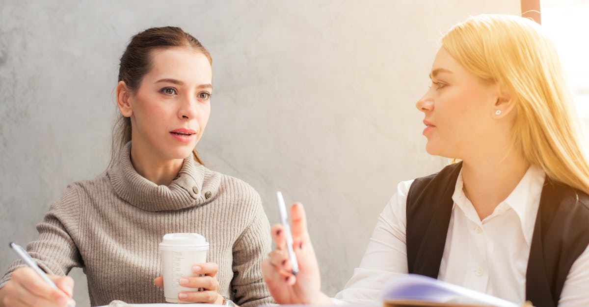 two women engaging in a professional conversation over coffee and notes