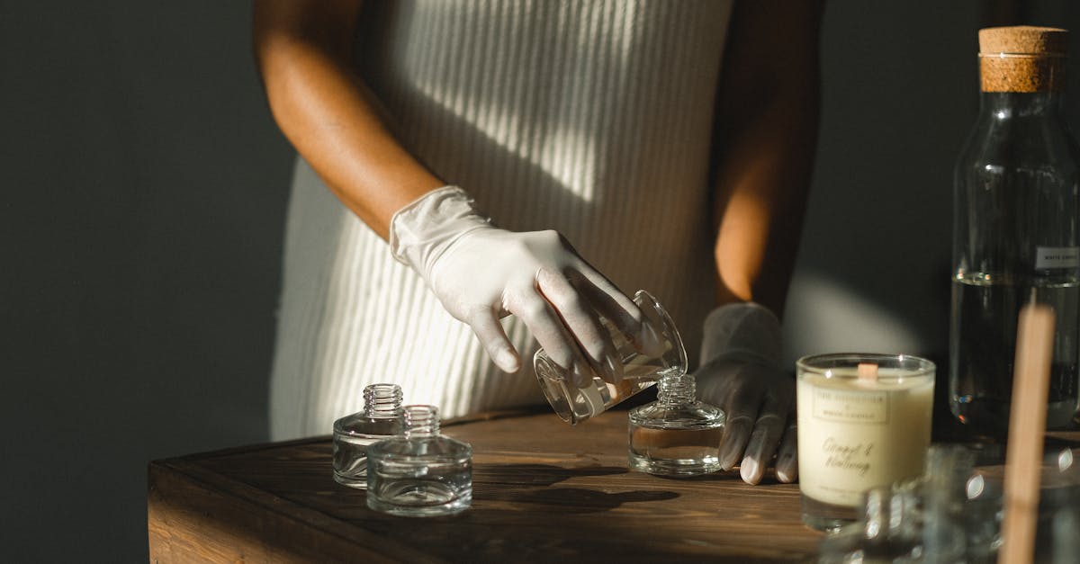 unrecognizable crop african american female pouring essential oil in glass bottle while making liqui