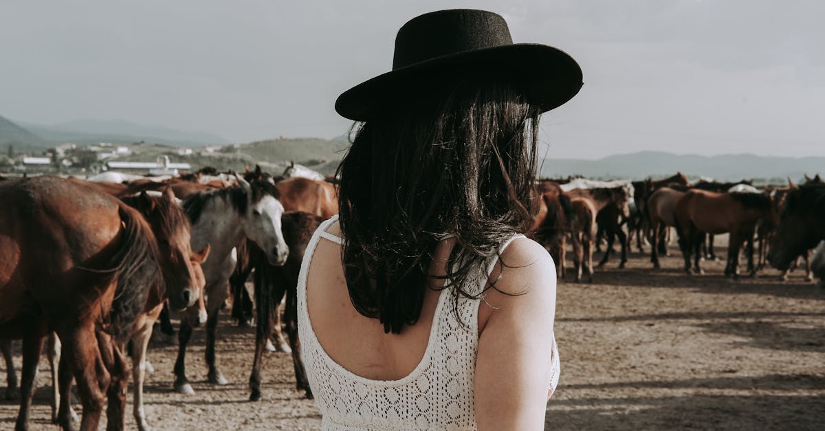 woman in cowboy hat herding a group of horses in the rural countryside