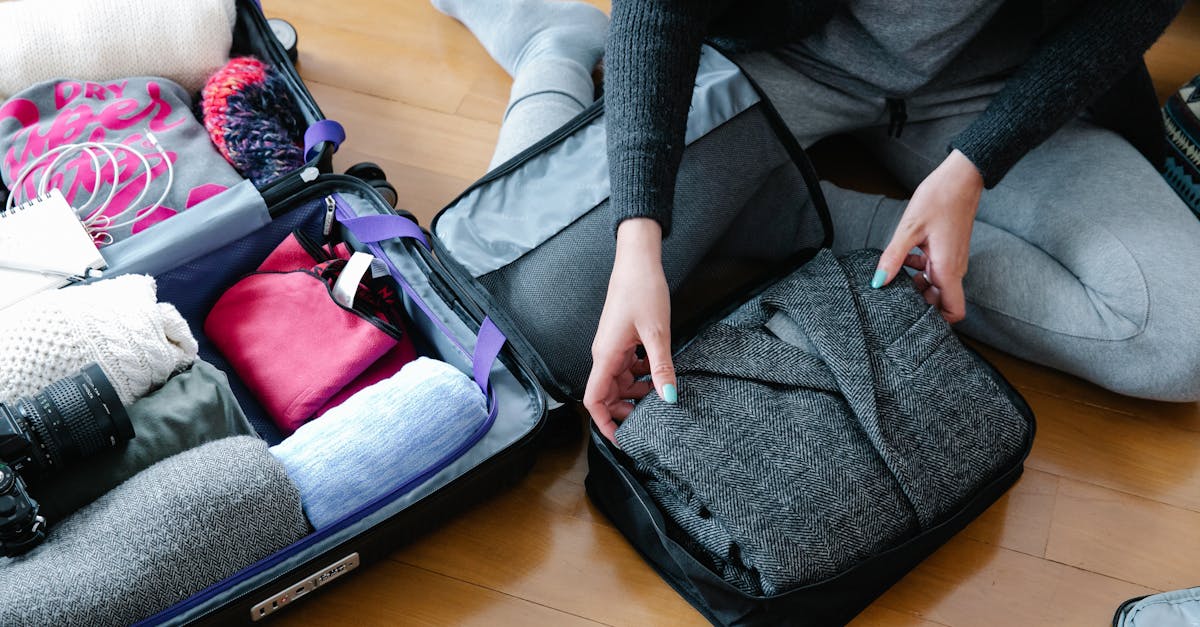 woman organizes clothing and camera gear in a suitcase for travel